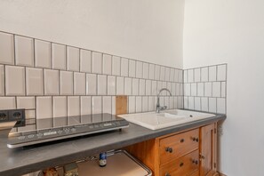 A kitchen with a black induction cooktop, a white sink, and wooden cabinets.