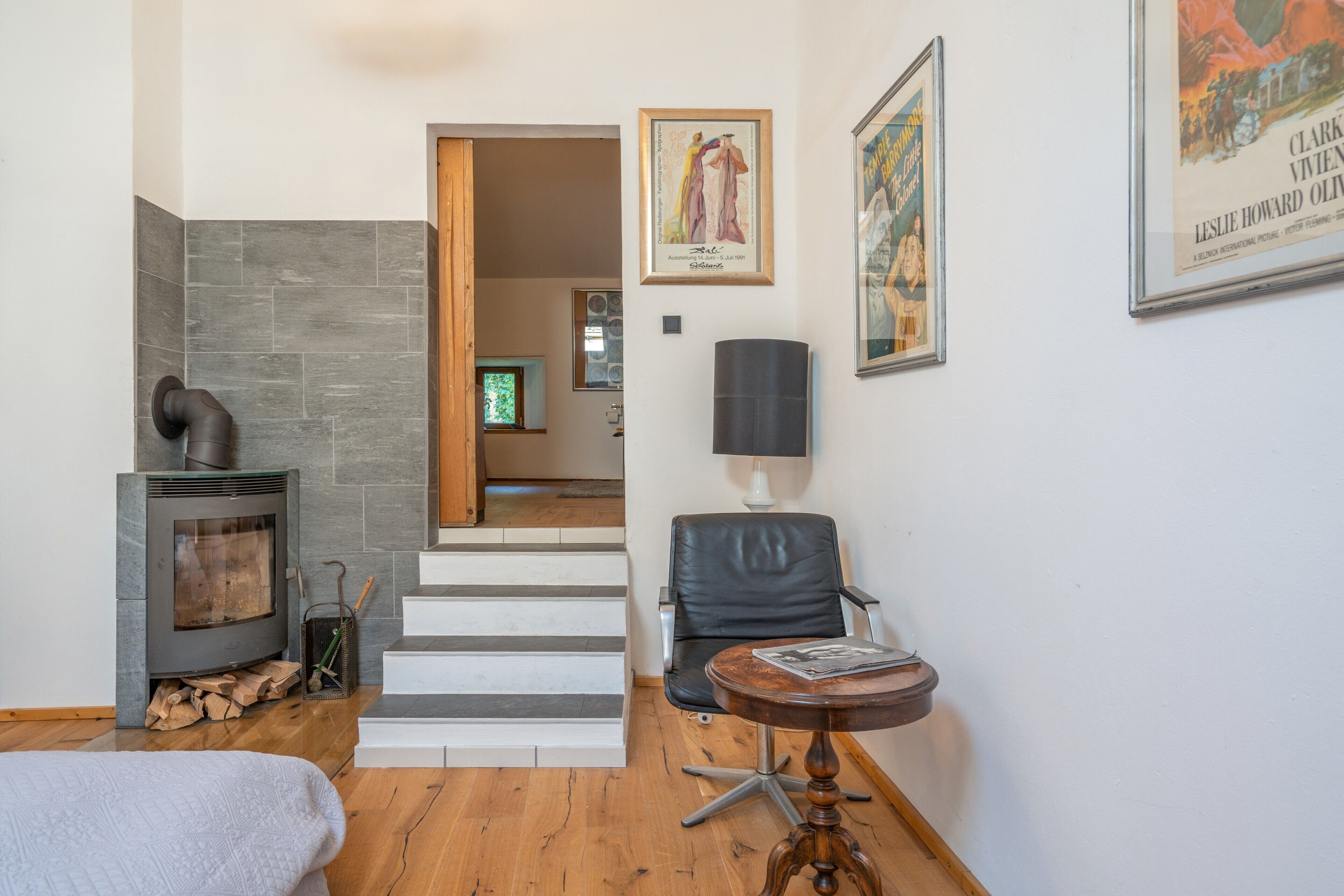A modern living room with a fireplace, a staircase, and a dining area.