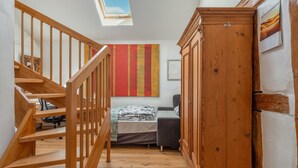 A room with a wooden staircase, a bed, a wardrobe, and a large window. - Holiday Apartment in Kipfenberg – 1 Bedroom / Sleeping Gallery / 2 Bathrooms (Kipfenberg)