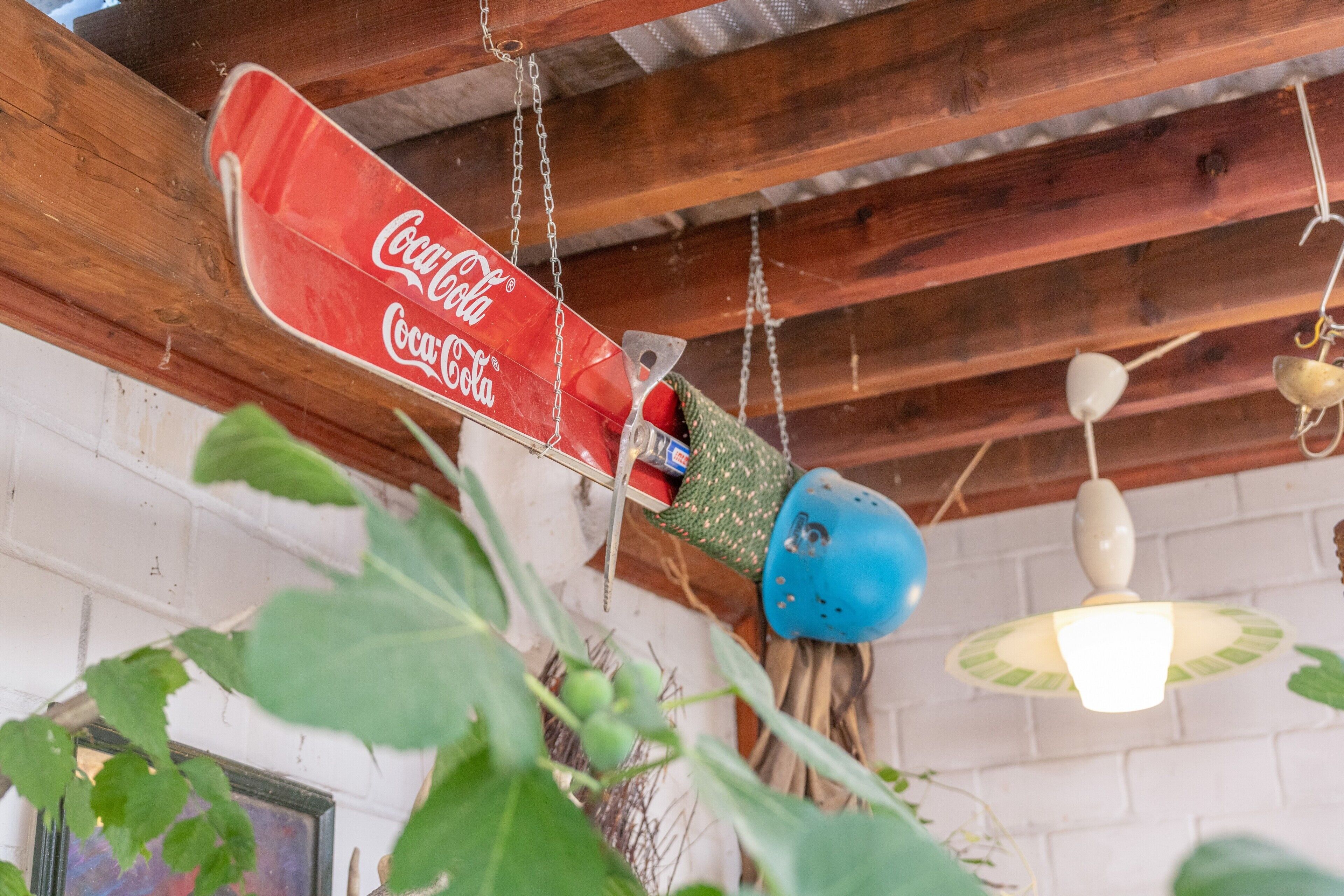 Ein hängendes Coca-Cola-Schild, rustikale Holzbalkendecke und eine weiße Backsteinwand.
