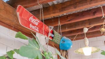 Ein hängendes Coca-Cola-Schild, rustikale Holzbalkendecke und eine weiße Backsteinwand.