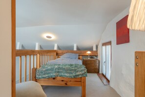 A bedroom with a wooden bed, a nightstand, a lamp, and a red artwork on the wall.