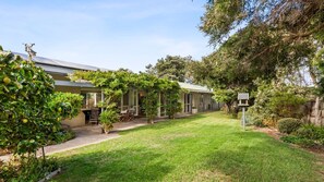 Una propietat residencial amb terrassa coberta, gespa i diverses plantes.