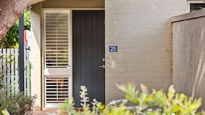 A residential entrance with a dark-colored door, a white-framed window with blinds, and a number '25' on the wall. - The Quiet Nook - Point Lonsdale (Point Lonsdale)