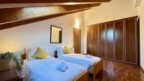 Ein Schlafzimmer mit zwei Betten, einem Holzschrank und einem Spiegel an der Wand.