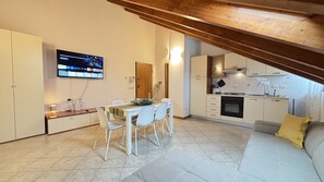 Un espai vital reduït amb zona de menjador, petita cuina i sofà.