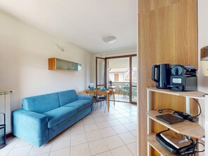 A modern living room with a blue sofa, a coffee machine, and a flat-screen TV on a wooden shelf. - Blue Nest Garda by Booking Lake Garda (Manerba del Garda)