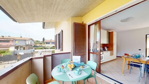 Un balcon avec une table dressée pour le repas, des chaises et une vue sur le quartier.
