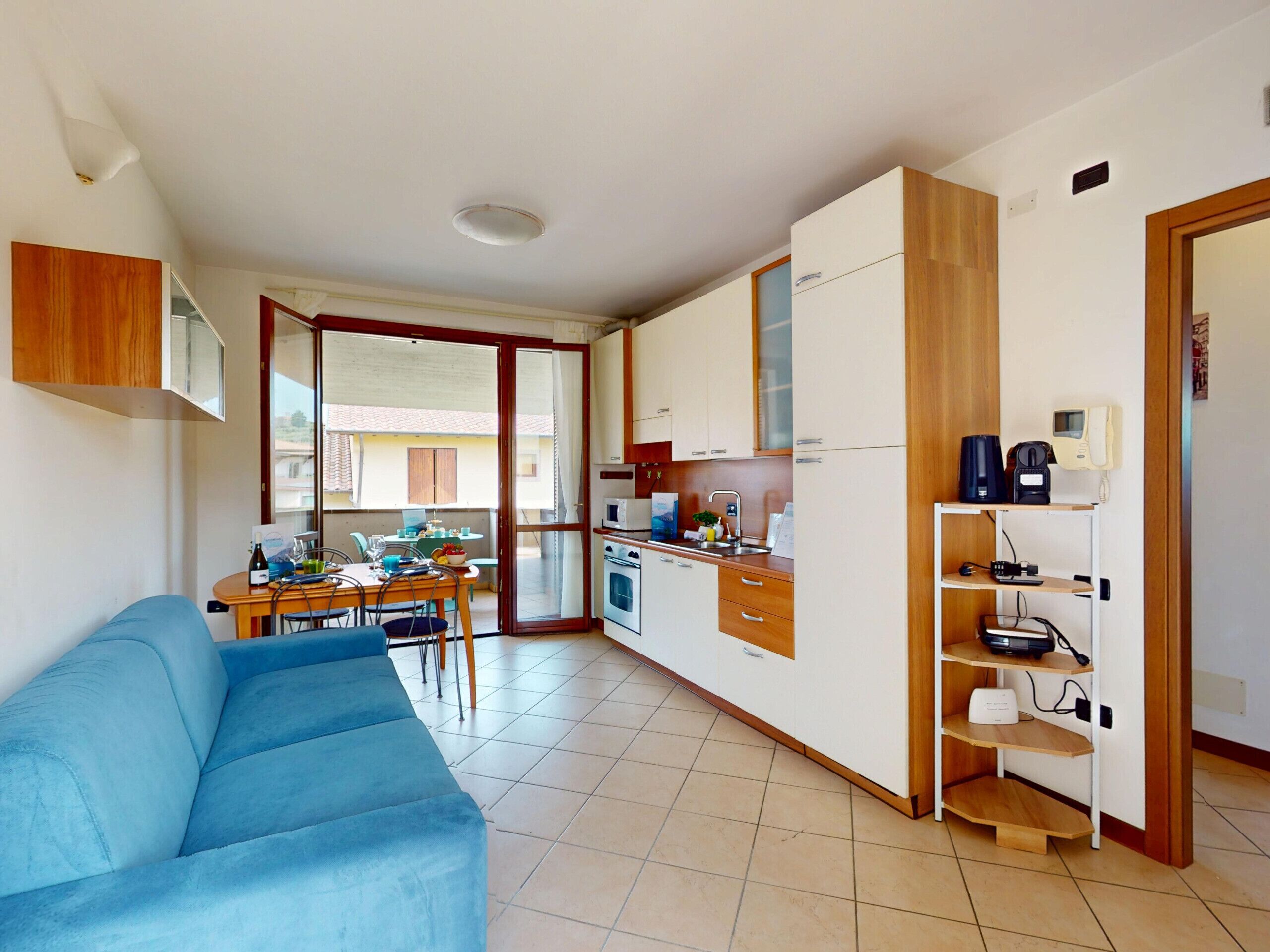 Een ruimtelijk ingerichte leefruimte met een kitchenette, een eethoek en een bank.