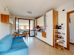 A compact living space with a kitchenette, a dining area, and a sofa. - Blue Nest Garda by Booking Lake Garda (Manerba del Garda)