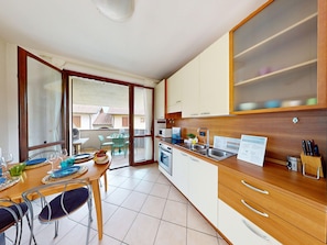 A modern kitchen with a dining area, large windows, and a view of the outside. - Blue Nest Garda by Booking Lake Garda (Manerba del Garda)
