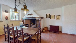 Een eetruimte met een houten tafel en stoelen, een open haard en een rustieke inrichting.