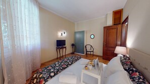 Ein Hotelzimmer mit Bett, Schreibtisch, Stuhl, Fernseher und einer Tür.
