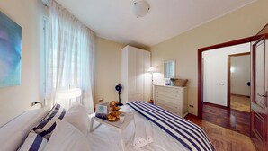 Een hotelkamer met een bed, nachtkastje, lamp, kaptafel en een spiegel.