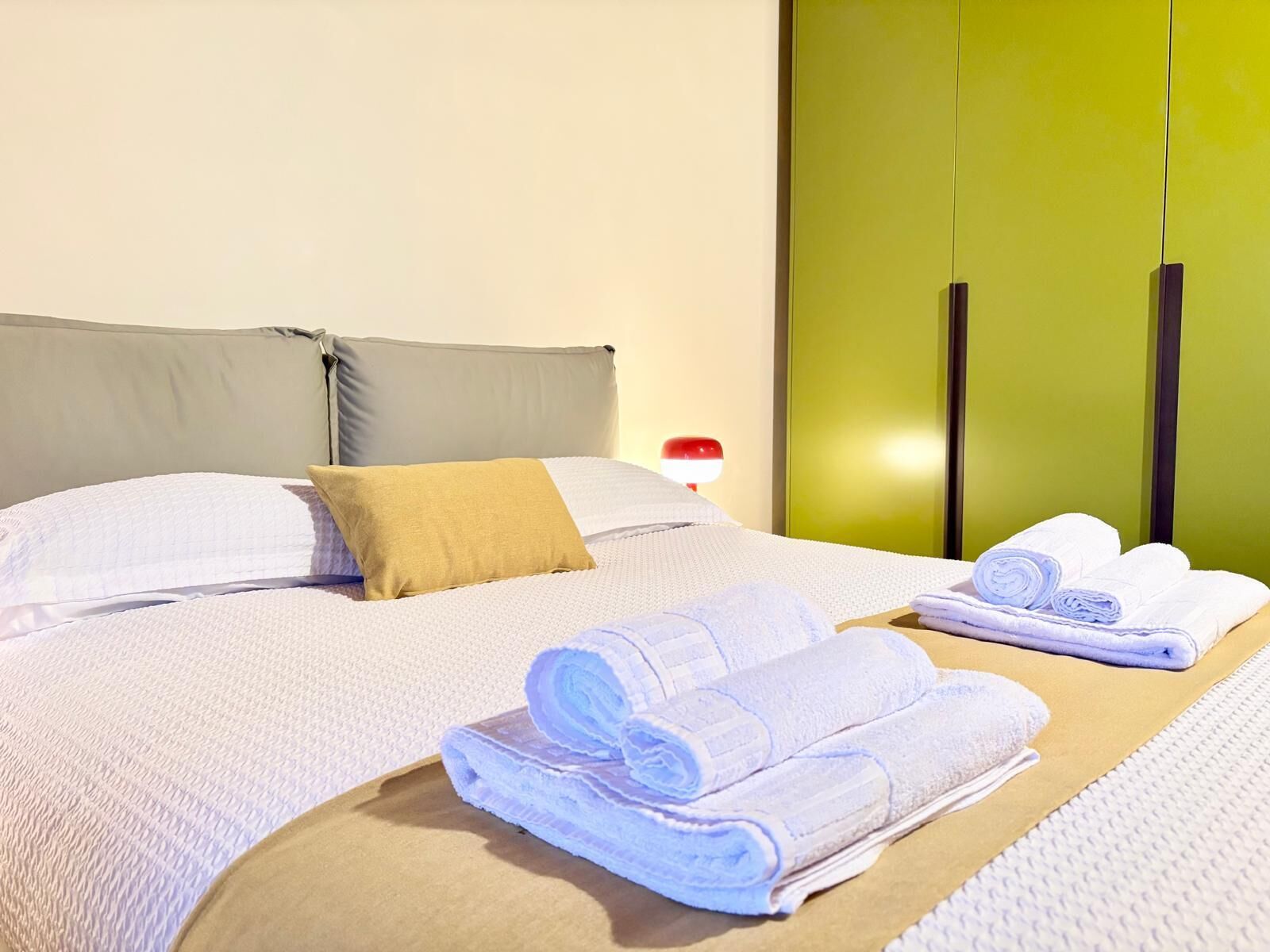 Une chambre d’hôtel avec un lit, des oreillers, une lampe de chevet et des serviettes soigneusement pliées sur le lit.