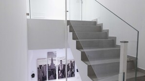 Una scala con ringhiera in vetro e un quadro con una veduta della città sulla parete.