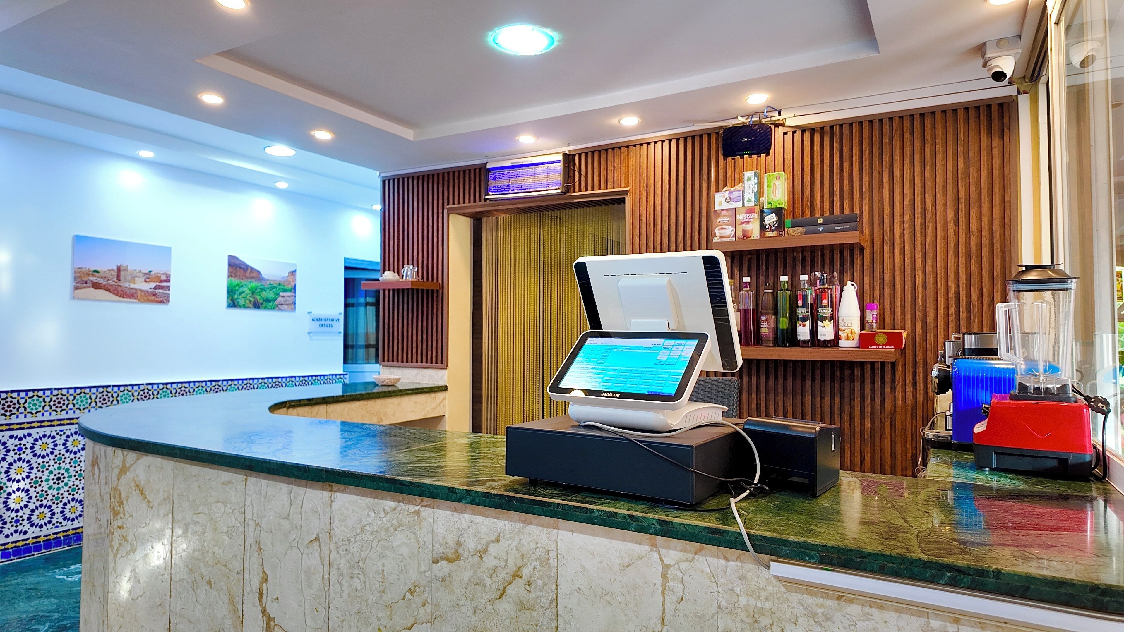Een hotel receptie met een marmeren balie, een digitaal incheckpunt, een houten wandpaneel en een uitzicht op de lobby.