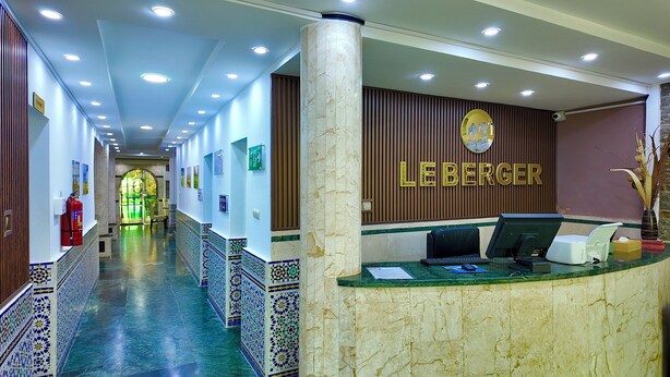 Zona de recepción de un hotel con un mostrador de mármol, un extintor y un cartel en la pared.