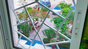 A view through a window with a geometric pattern, a pool, and a parking area with cars.