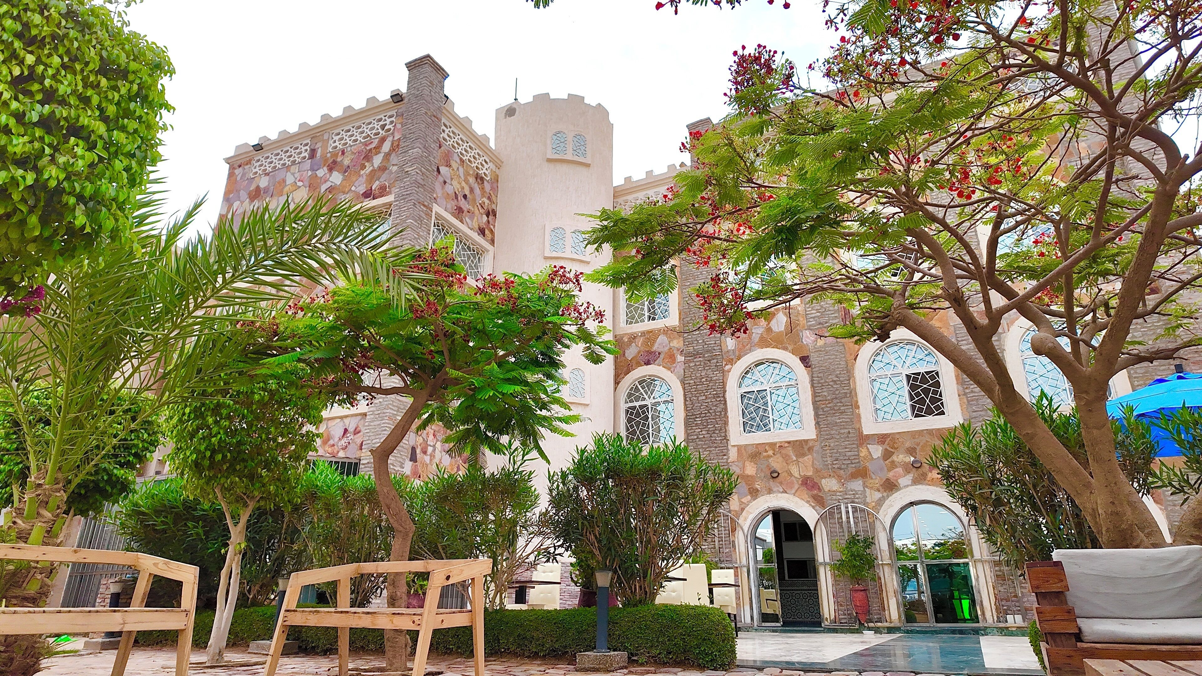 A courtyard with a stone building, benches, and trees.