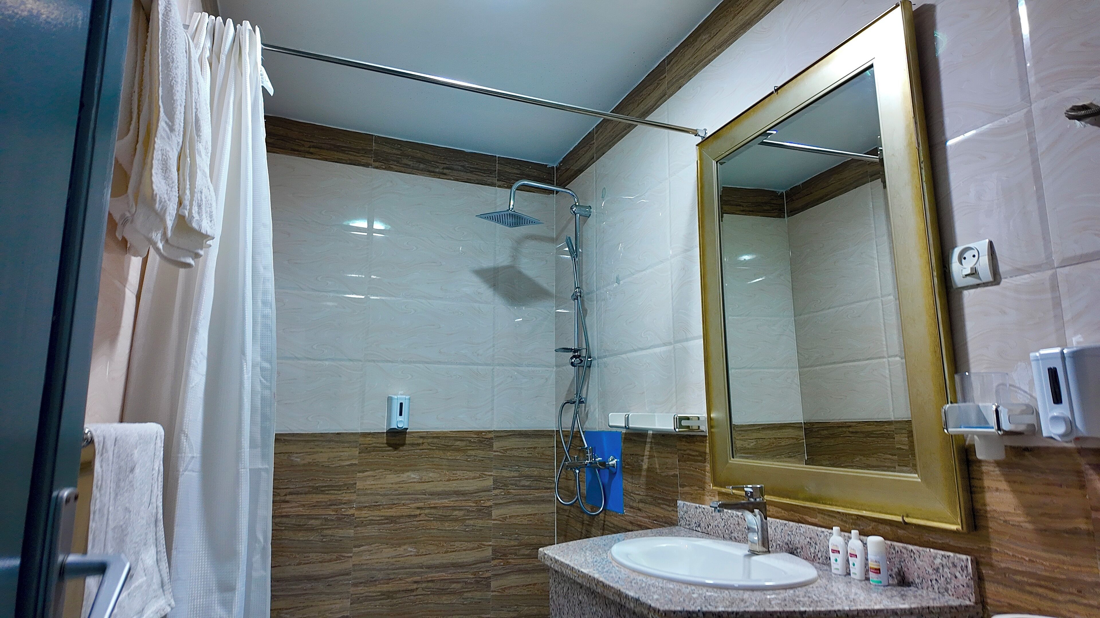 Ein Badezimmer mit Dusche, Waschbecken und Spiegel.