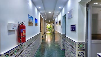 A corridor with a fire extinguisher, a first aid kit, and a sign indicating restrooms.