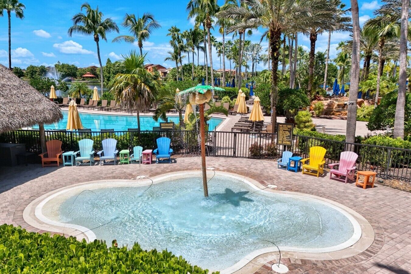 A pool area with a hot tub, lounge chairs, and a sign indicating a restroom.