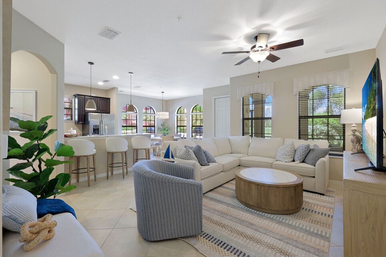 A spacious living room with a sectional sofa, a round coffee table, and a dining area with bar stools.