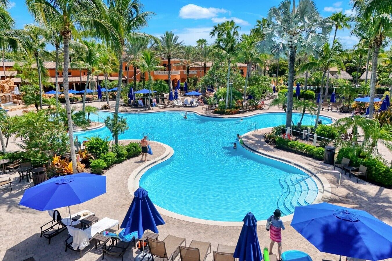 A resort pool area with multiple swimming pools, lounge chairs, and umbrellas.