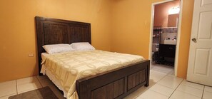 Ein Schlafzimmer mit einem Holzbett, einem Nachttisch und einer Tür zu einem Badezimmer.