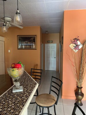 A dining area with a table, chairs, a decorative bowl, and a vase with dried plants. - Alluring Ambrosia (Arouca)