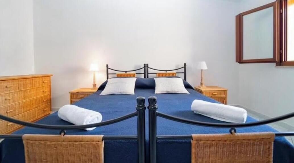 Ein Hotelzimmer mit einem Bett, zwei Nachttischen, einer Holzkommode und einem Spiegel an der Wand.
