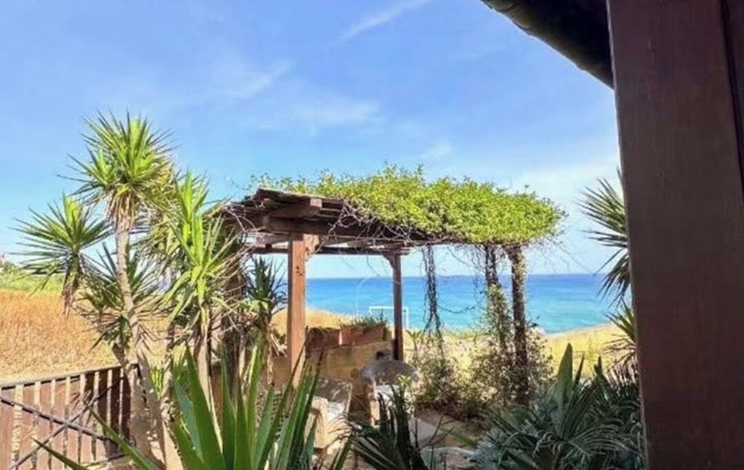 A wooden pergola with a view of the beach and ocean.