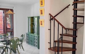 Un coin repas avec une table et des chaises en verre, un meuble vert et un escalier en bois.