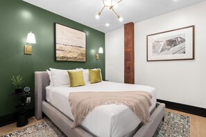 A modern bedroom with a bed, green walls, and artwork. - Eleven48 by NOLA Luxury Collection (New Orleans)