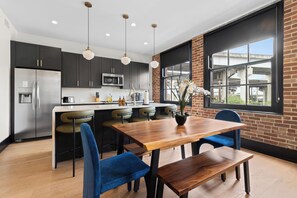 A modern kitchen with dark cabinets, stainless steel appliances, and a central island with seating. - Eleven48 by NOLA Luxury Collection (New Orleans)