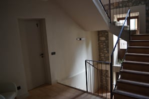A staircase with a stone wall and a door leading to another room. - Can Hortafa - Country House in Tortellà - Cortada de la Cellera (Tortellà)