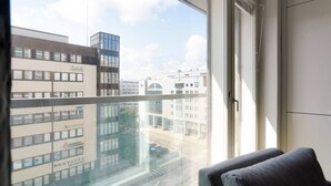 A room with a large window, a view of city buildings, and a door. - Mall of Tripla apartments by Come in (Helsinki)