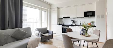 A modern living room with a sofa, a coffee table, and a dining area with chairs and a table.