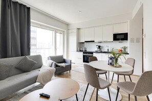 A modern living room with a sofa, a coffee table, and a dining area with chairs and a table.