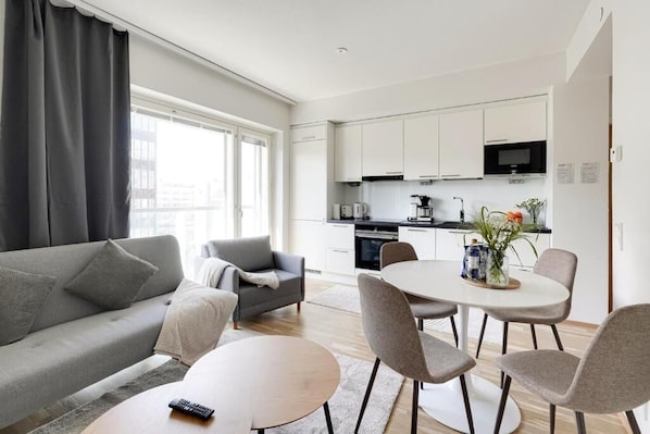 A modern living room with a sofa, a coffee table, and a dining area with chairs and a table.