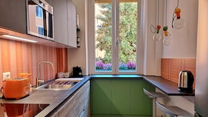 Cozinha moderna com forno embutido, pia e janela com vista para áreas verdes.