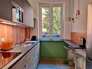 A modern kitchen with a built-in oven, a sink, and a window with a view of greenery. - St.Peter's Basilica Apartment (Roma)