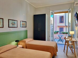 A hotel room with two beds, a wardrobe, a desk with a chair, and a view of the street outside. - St.Peter's Basilica Apartment (Roma)