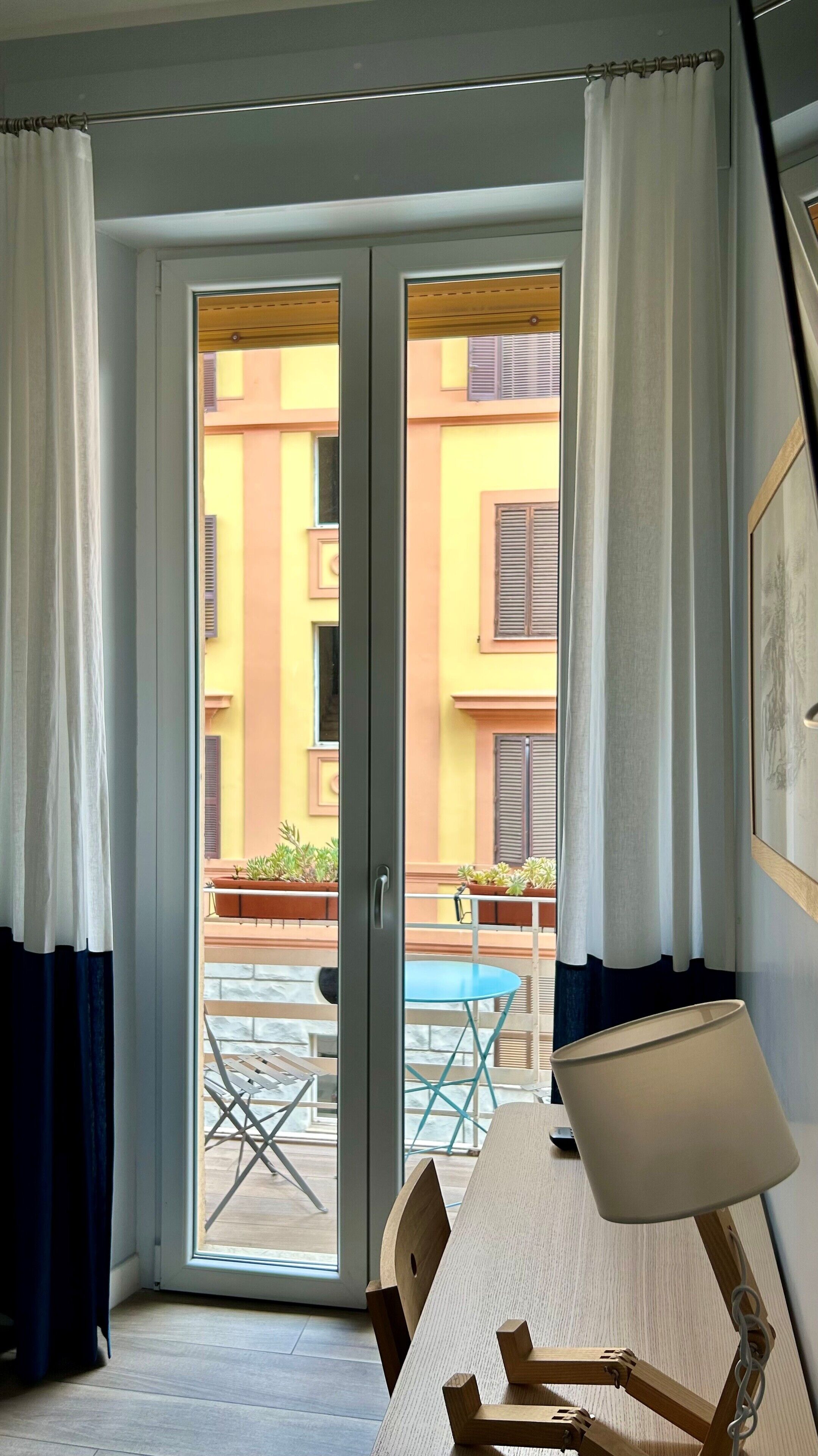 Une pièce dotée d’une porte-fenêtre coulissante donnant sur un espace extérieur aménagé avec une table et des chaises.