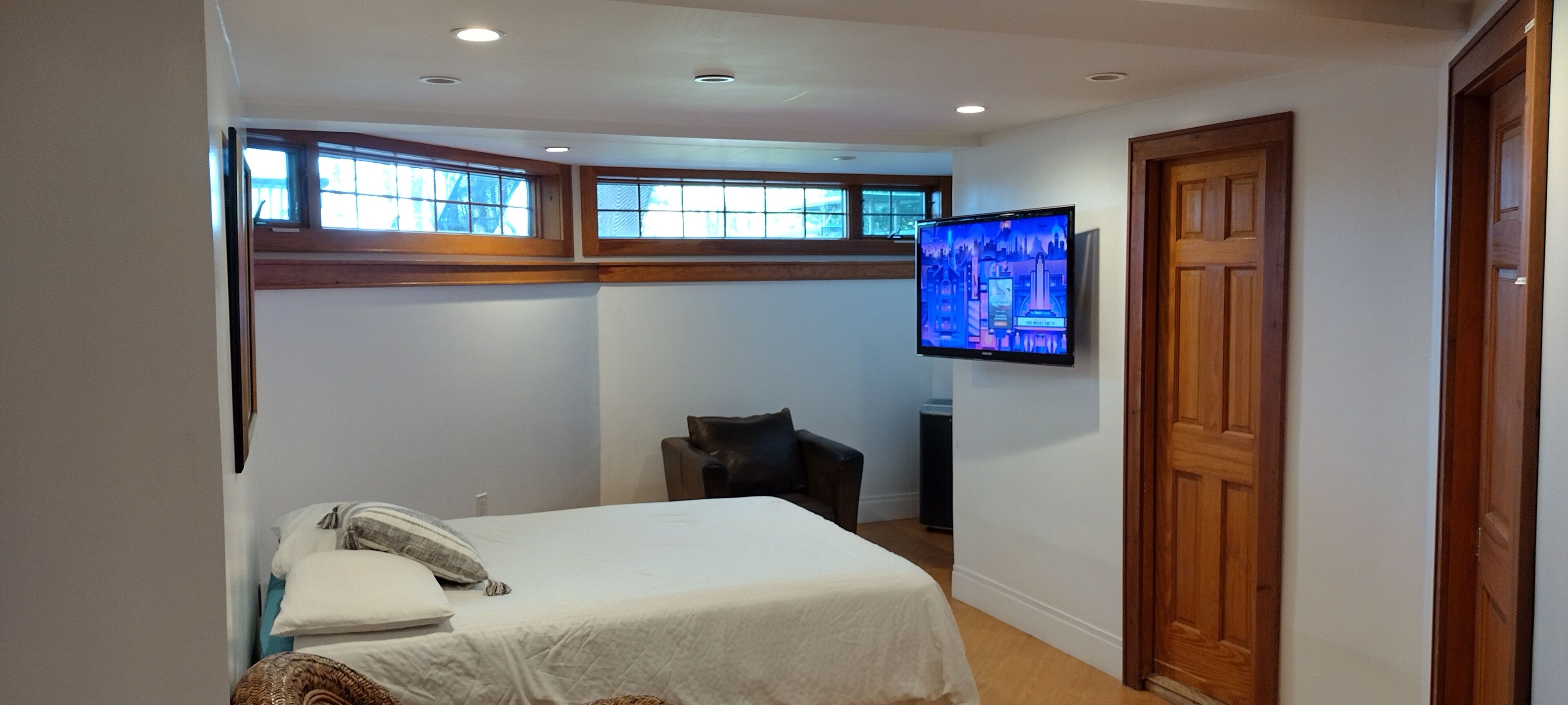 Een slaapkamer met een bed, een aan de muur bevestigde televisie en een raam.