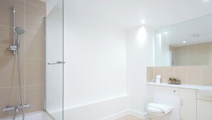 Une salle de bain moderne équipée d’une baignoire, de toilettes et d’une douche.
