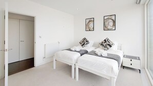 Une chambre moderne avec deux lits, un dressing et des œuvres d’art accrochées au mur.