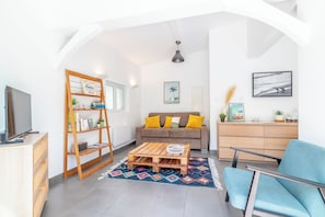 A modern living room with a sofa, coffee table, and a TV on a wooden cabinet. - A 10-minute walk from the beach, a charming little house with a south-facing terrace (Anglet)