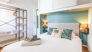 Een slaapkamer met een bed, twee bedlampen, een hoofdbord, een wandplank en een houten ladder.